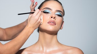 Woman with blue eyeshadow getting her makeup done at the spa