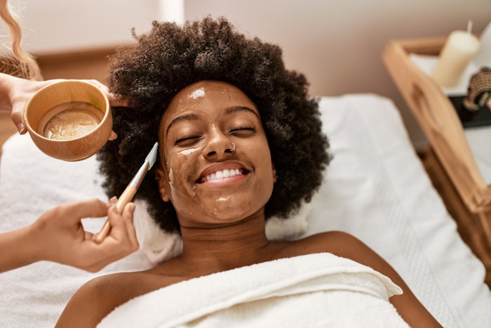 young woman smiling confident having facial treatment at beauty center