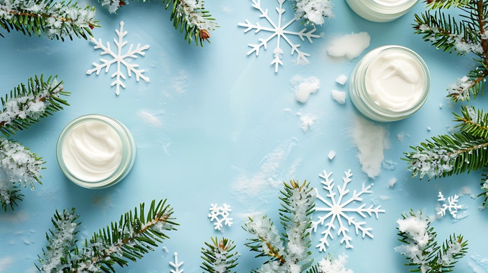 Winter Skin Care products fir branches and snowflakes on blue background