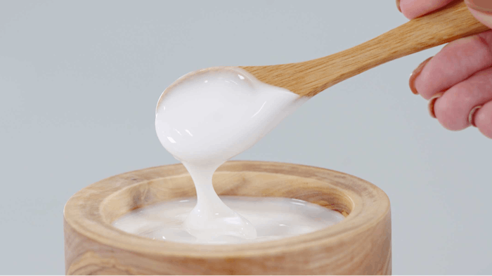 wooden bowl and spoon scooping creamy white emulsion