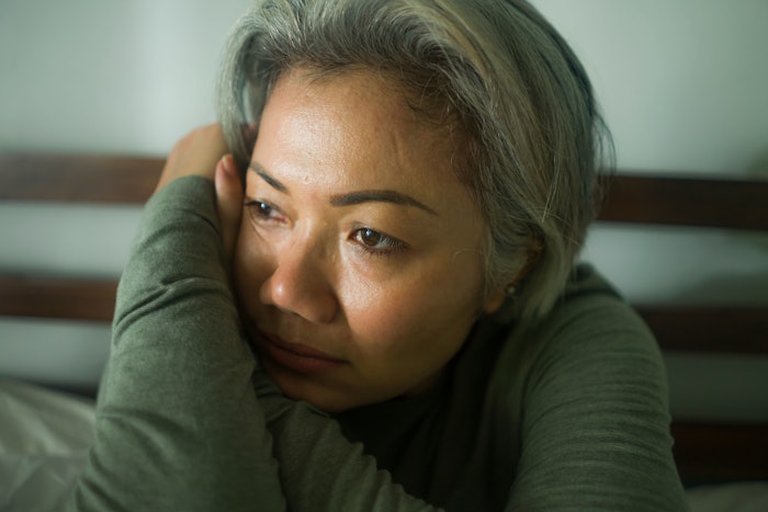 attractive middle aged woman with grey hair sad and depressed in bed feeling scared and lonely thinking worried