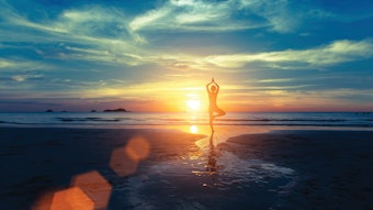 Yoga silhouette at sunset on the sea shore. Calm and self-control.