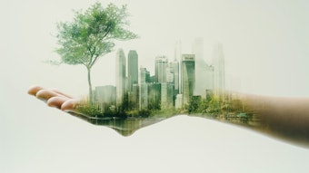 Hand holding sustainable cityscape with lush green trees
