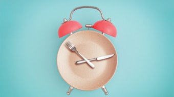 Alarm clock and plate with cutlery. Concept of intermittent fasting, lunchtime, diet and weight loss