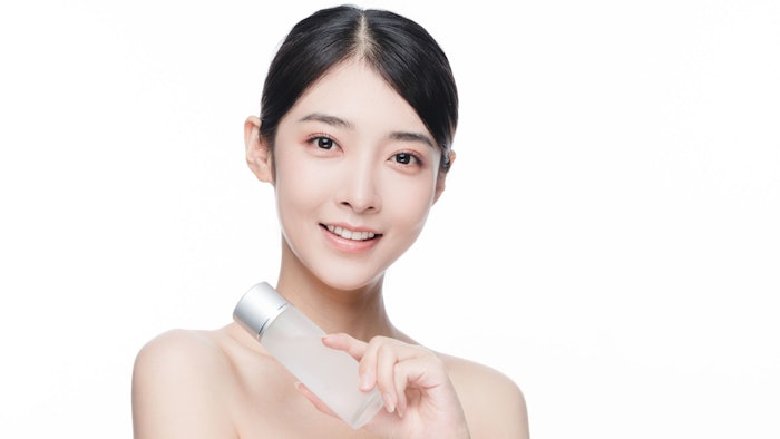 beautiful Asian woman isolated on white background holding essence skin care product