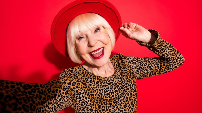 happy mature woman hat leopard shirt red bg