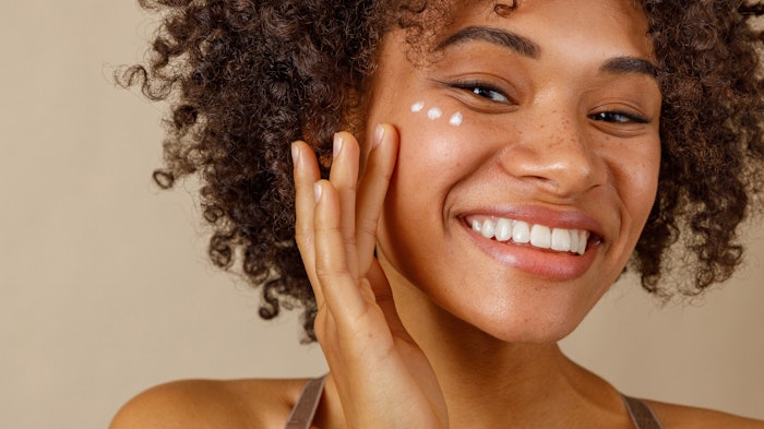 Young Beautiful Multiracial Girl Smiling Using Facial Skin Care