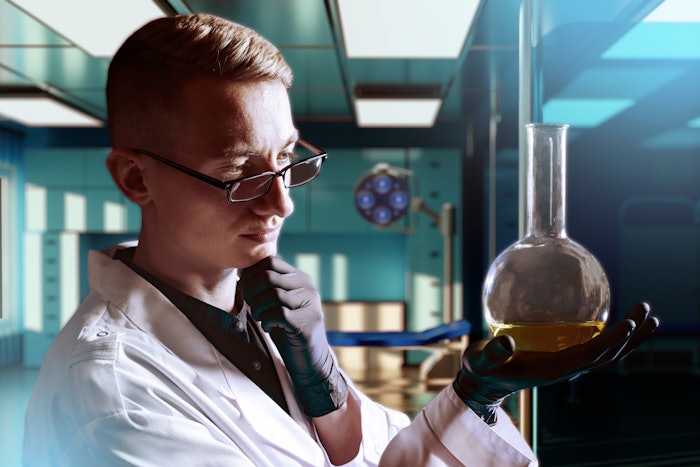 Chemist In Lab Looking At Liquid In Flask Thinking Adobe Stock 853750305