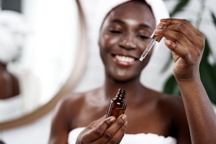 Beautiful Young Black Woman Towel Mirror Skin Serum Up Close Dropper Adobe Stock 1511571612