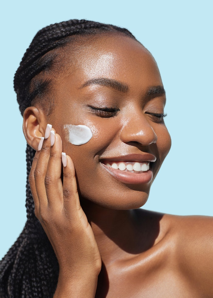 Beautiful Black Woman Using Skin Cream On Face Smiling Relaxed Adobe Stock 1697728328