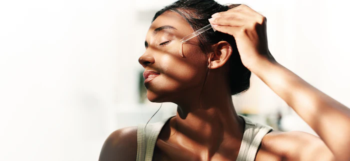 Young woman adjusting glasses while looking to the side in natural sunlight