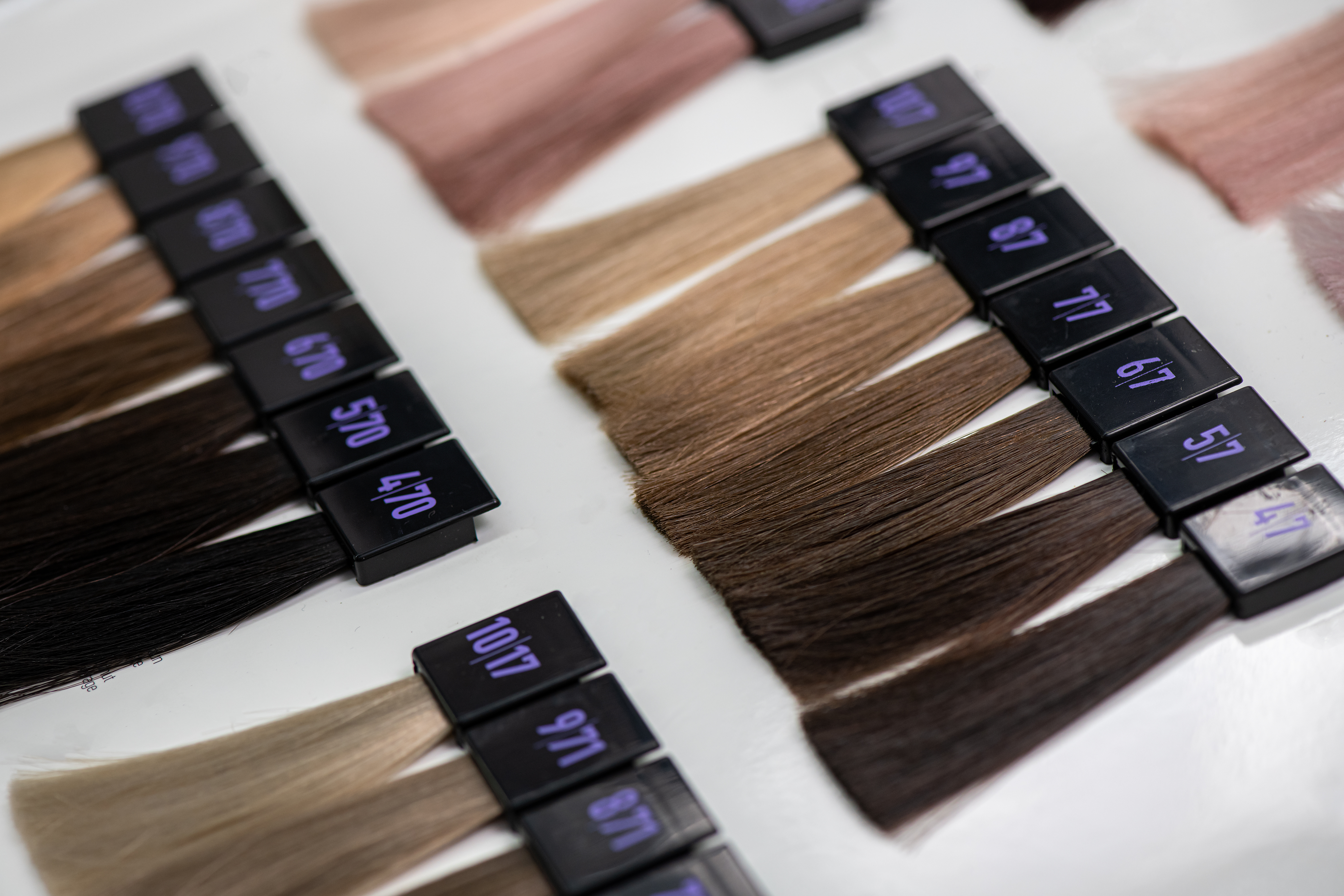 Hair color swatches and extensions arranged in rows, displaying various shades from black to blonde with black numbered labels