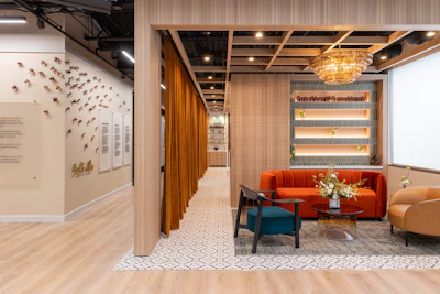 Modern office lounge with orange sofa, wooden partitions, geometric patterned flooring, and decorative bird wall art installation