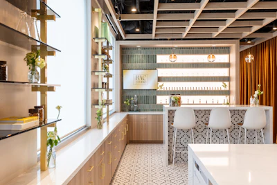Modern luxury spa or retail interior with white counter, patterned floor tiles, gold shelving, and warm lighting