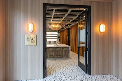 BAC Studio entrance with illuminated signage, modern interior with wooden accents and bar seating visible through glass doors