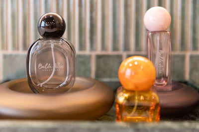 Luxury perfume bottles with spherical caps displayed on wooden platforms against striped background