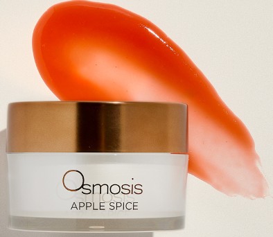 Osmosis Apple Spice skincare cream in glass jar with gold lid and coral-colored product swatch
