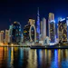 Dubai downtown skyline at night with illuminated skyscrapers and glowing Ferris wheel reflected in calm waterfront