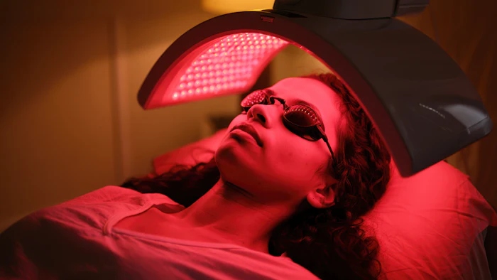 Person receiving red light therapy treatment under LED panel device