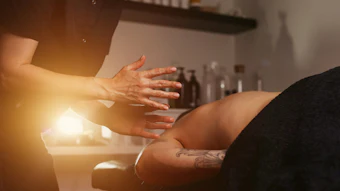 Hands during a therapeutic massage or spa treatment with warm golden lighting in a wellness setting