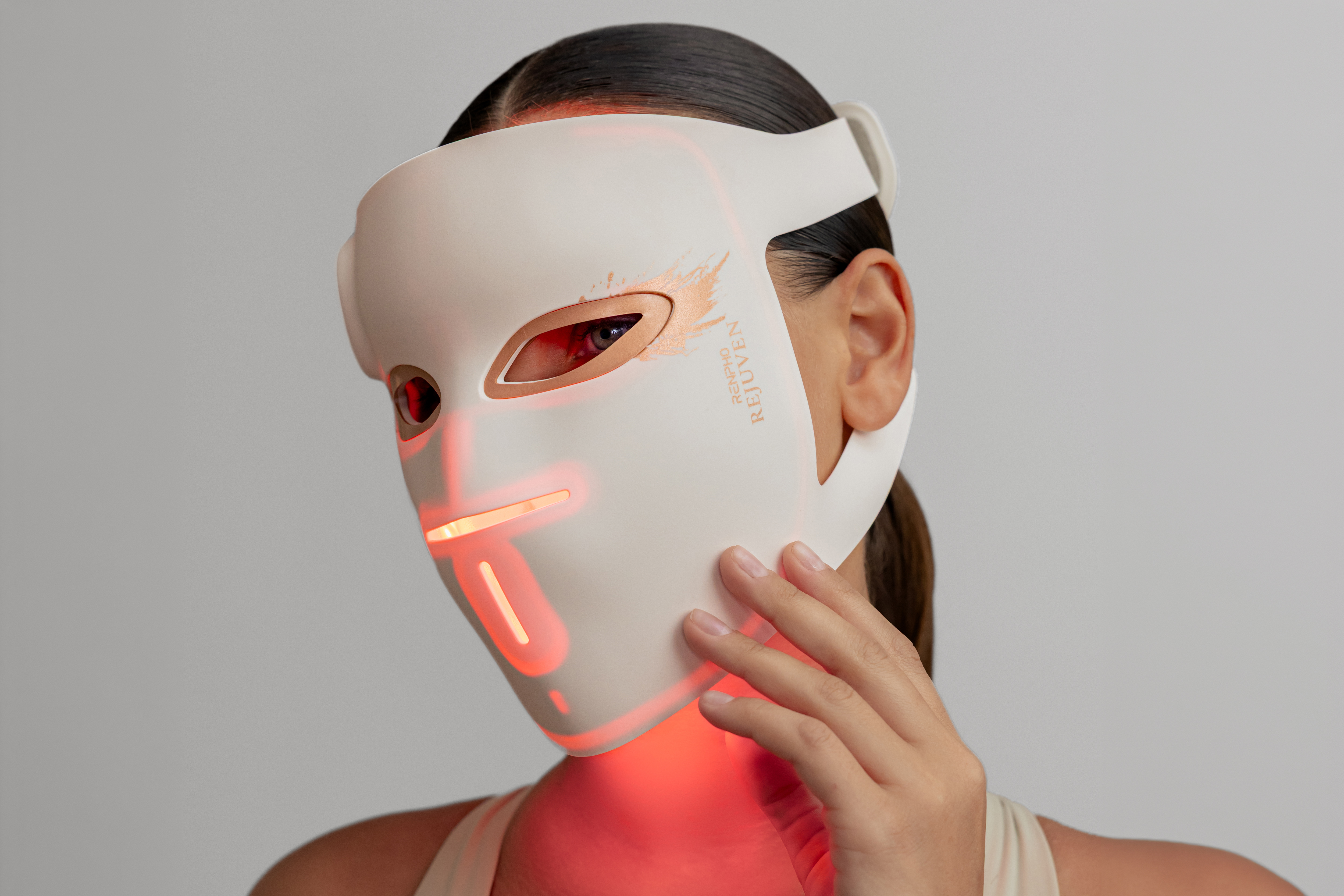 Person wearing white LED light therapy mask with red illuminated accents on face and chin area