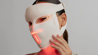 Person wearing white LED light therapy mask with red illuminated accents on face and chin area