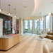 Modern luxury apartment lobby with wooden reception desk, contemporary seating, floor-to-ceiling windows overlooking city skyline