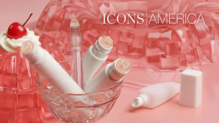 Beauty and skincare products displayed in a crystal bowl with pink cosmetic bottles and a cupcake-topped item against a gradient pink background