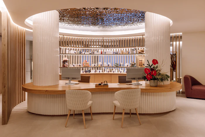 Luxury jewelry store interior with curved white counter, wooden accents, and illuminated display shelving