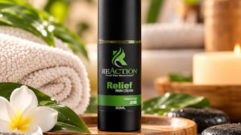 ReAction Relief Pain Cream 30ml bottle displayed in a spa setting with rolled towel, white flowers, smooth stones, and botanical elements